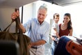 Senior white man packing car boot with holiday luggage, watched by his adult daughter and grandson Royalty Free Stock Photo