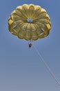 Senior white woman is parasailing.She is flying under yellow parachute in blue sky, smiling and opening her arms. Royalty Free Stock Photo