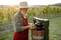 Senior winemaker with grapes near the winepress machine outdoors