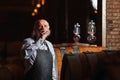 Senior winemaker tasting red wine near a big oak barrel Royalty Free Stock Photo