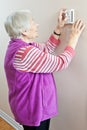 Senior woman adjusting her thermostat