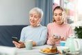 Senior woman and adult daughter sitting at table with cell phones Royalty Free Stock Photo