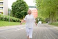 Senior Woman in All White Walking at the Street