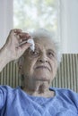 Senior woman applying eye drop on her eye