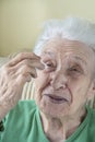 A senior woman applying eyedrops into her eyes by herself