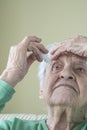 A senior woman applying eyedrops into her eyes by herself