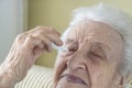 A senior woman applying eyedrops into her eyes by herself