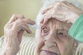 A senior woman applying eyedrops into her eyes