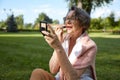 Senior woman applying lipstick doing makeup for charming smile Royalty Free Stock Photo