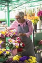 Senior woman arranges flowers on local flower market