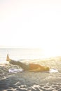 Senior woman exercising, stretching on yoga mat at the beach, doing leg raises