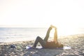 Senior woman exercising, stretching on yoga mat at the beach, doing leg raises