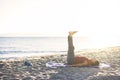 Senior woman exercising, stretching on yoga mat at the beach, doing leg raises