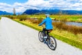 Senior woman biking along the Alouette River on the surrounding Pitt Polder at the town of Maple Ridge in British Columbia