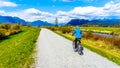 Senior woman biking along the Alouette River on the dyke surrounding Pitt Polder at the town of Maple Ridge in British Columbia