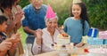 Senior woman, birthday cake and family in garden with applause, celebration and happy together for party. Man, women and Royalty Free Stock Photo