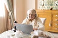 Senior woman plays video games with joystick on a laptop