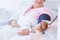 Senior woman with blood pressure monitor on her arm and young intern at hospital