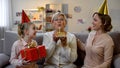 Senior woman blowing candle on cake, family congratulating granny, celebration