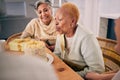 Senior woman blowing candles on her cake for birthday celebration at a house at a party with friends. Smile, happy and Royalty Free Stock Photo