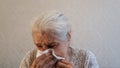 Senior woman blows her nose in a handkerchief.