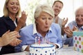 Senior Woman Blows Out Birthday Cake Candles At Family Party Royalty Free Stock Photo