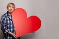 Senior woman in blue shirt showing big red heart banner background Royalty Free Stock Photo