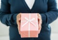 Senior woman in blue sweater is holding a pink gift box Royalty Free Stock Photo