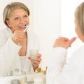 Senior woman brushing teeth bathroom mirror Royalty Free Stock Photo