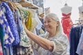 Senior Woman Buying Used Sustainable Clothes From Second Hand Charity Shop Or Thrift Store