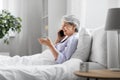 senior woman calling on smartphone in bed at home Royalty Free Stock Photo