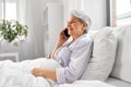 senior woman calling on smartphone in bed at home Royalty Free Stock Photo