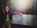 Senior woman Carrying a walking stick travel through a forest hands placed on blank steel sign