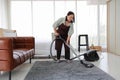 Senior woman cleaning the carpet with vacuum cleaner in the living room
