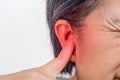 Senior woman closes ears with fingers to protect from loud noise