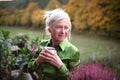 Senior woman with coffee standing outdoors on terrace, resting.