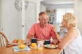 Senior Woman Comforting Man Suffering With Depression At Breakfast Table At Home