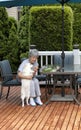 Senior woman communicating with her pet dog while cleaning herbs outside on the home deck Royalty Free Stock Photo