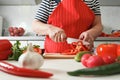 Senior woman cooking at home in the kitchen, cutting bell peppers on a wooden board. Healthy fresh food