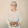 Senior woman cooking in the kitchen - eating and cooking healthy for her family; putting some potates in the oven, enjoying active