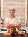 Senior woman and cooking with knife in kitchen or confident, tomato or carrots for diet. Female chef or portrait with Royalty Free Stock Photo