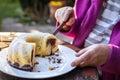 Senior woman cutting slice of bundt cake outdoors Royalty Free Stock Photo