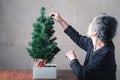 Senior woman decorating the Christmas tree while sitting in a living room at home Royalty Free Stock Photo