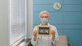 Senior woman doctor with disposable mask holds blackboard with word Vaccine