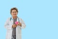 senior woman doctor with stethoscope smile holding heart on blue background.healthcare and medical concept