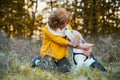 A senior woman with a dog in an autumn nature at sunset.