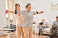 Senior woman doing gymnastic exercise in living room with her caregiver