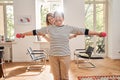 Senior woman doing gymnastic exercise in living room with her caregiver