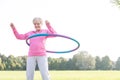 Senior woman doing gymnastic with hula hoop in park