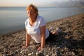 Senior woman doing yoga performing asanas and enjoying life on the beach sea, sunset time Royalty Free Stock Photo